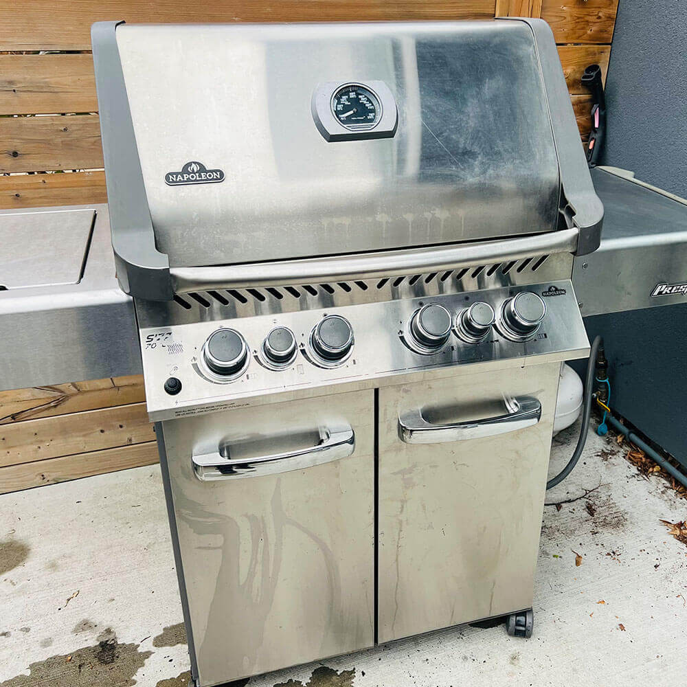 HRPM technician reassembling a barbecue grill on a patio, showcasing the spotless, gleaming finished product.