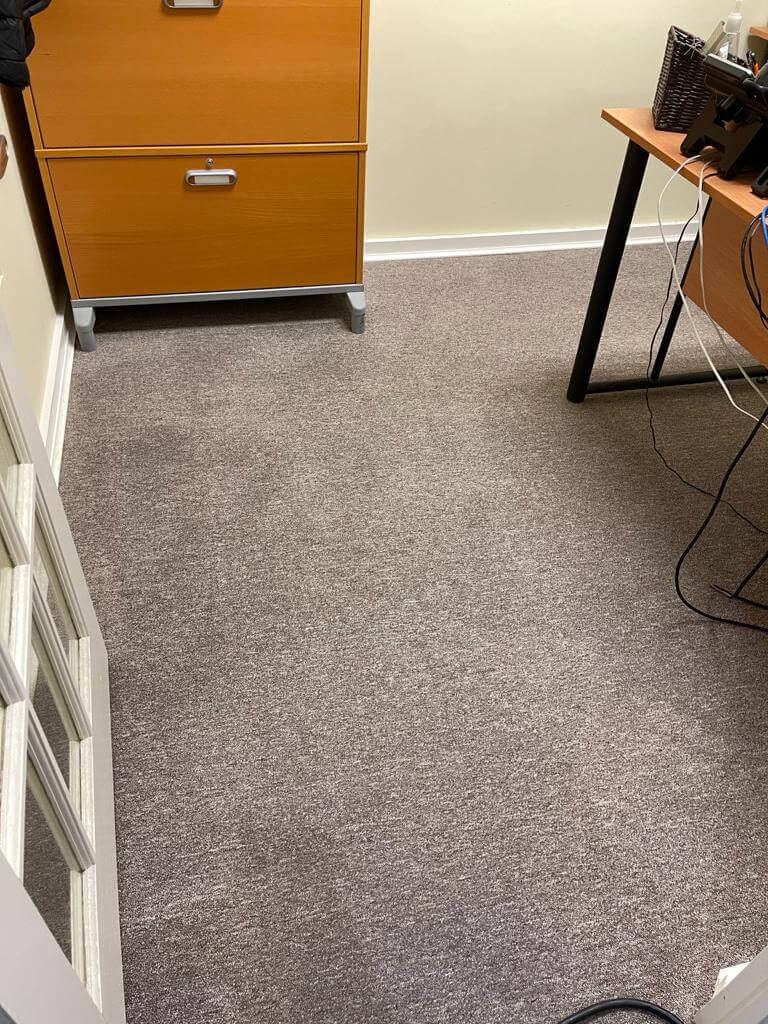 Technician from HRPM applying a targeted stain-removal solution to a red wine spill on light-colored carpet.