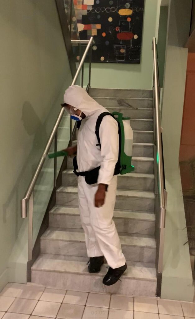 Technician using electrostatic sprayer for stair handrail disinfection cleaning by HRPM.