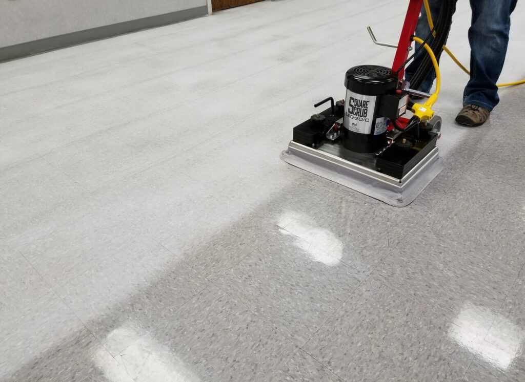 High-speed square scrub floor machine cleaning vinyl tile corridor in school hallway