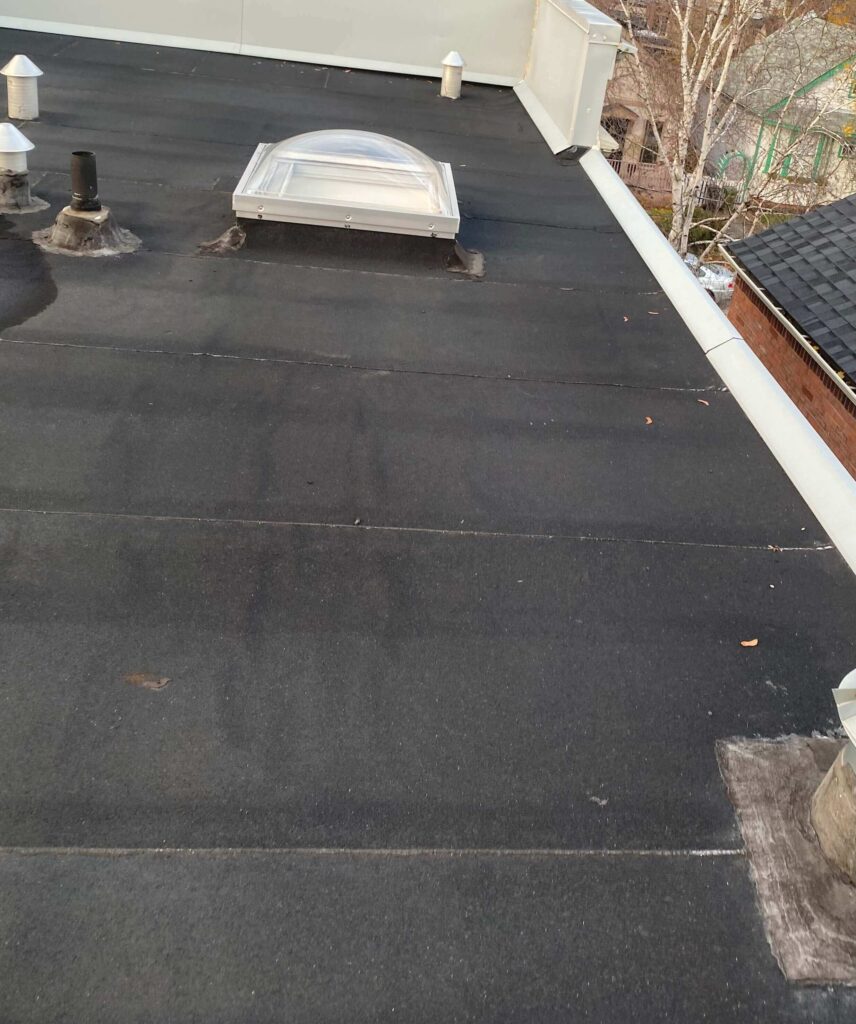 HRPM technician inspecting the flat-roof edge and drains for proper water flow after cleaning.