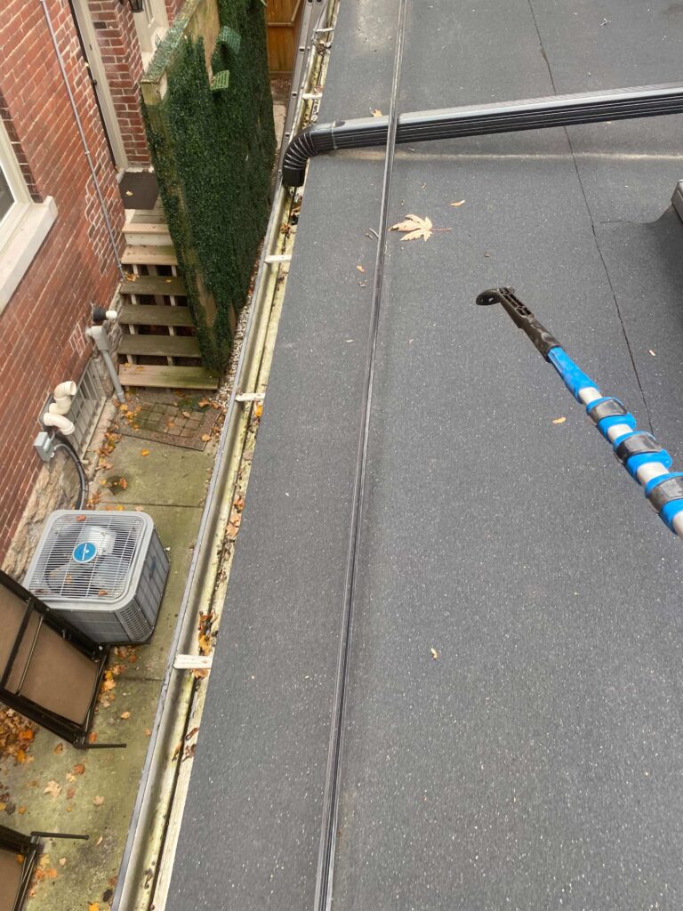 Debris and dirt accumulated along the edge of a flat roof on a Toronto home before cleaning by HR Property Maintenance (HRPM)
