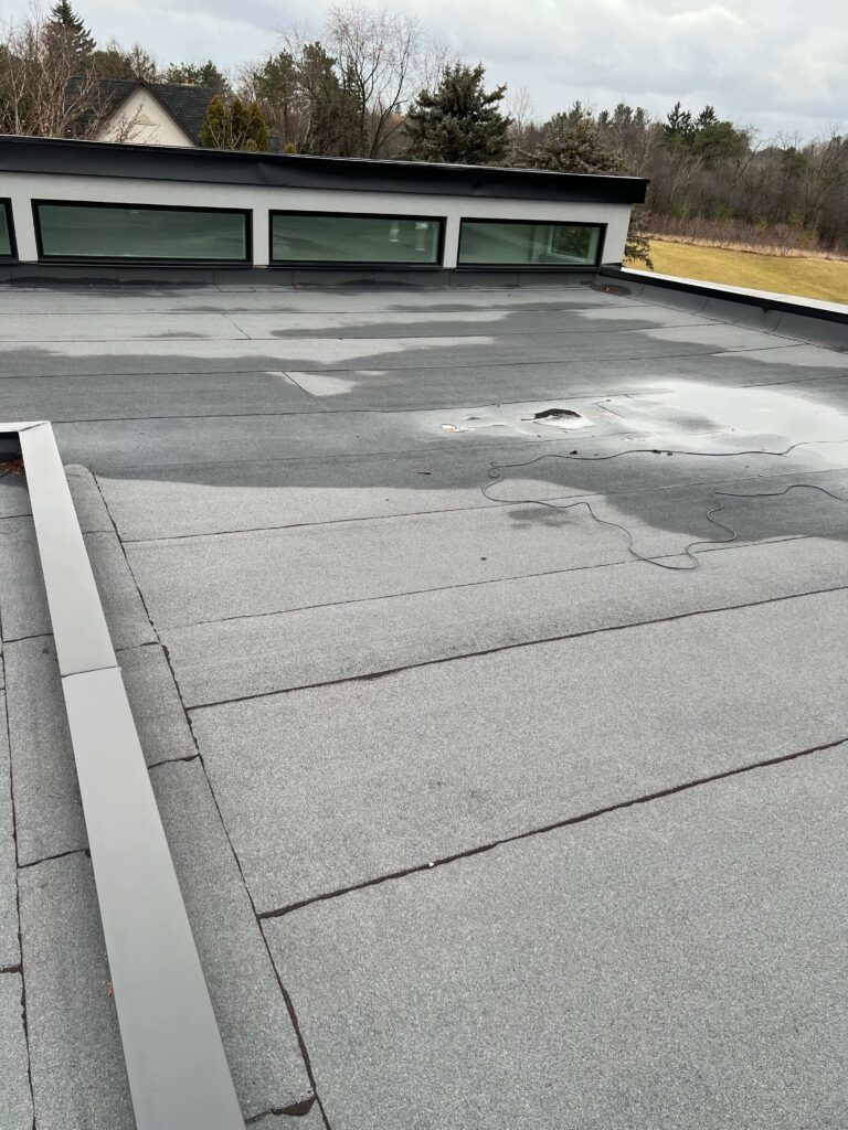 HRPM technician hand-removing moss and organic buildup from a flat roof surface in the Greater Toronto Area.