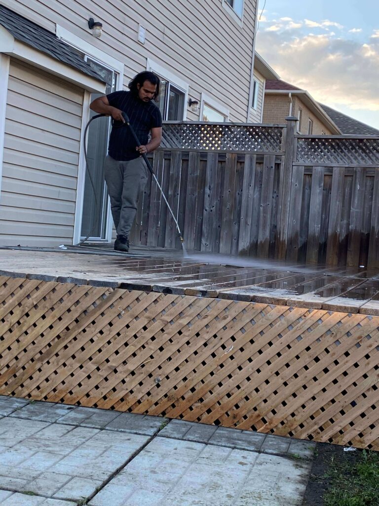 HRPM technician cleaning a stained concrete driveway with a commercial pressure washer.