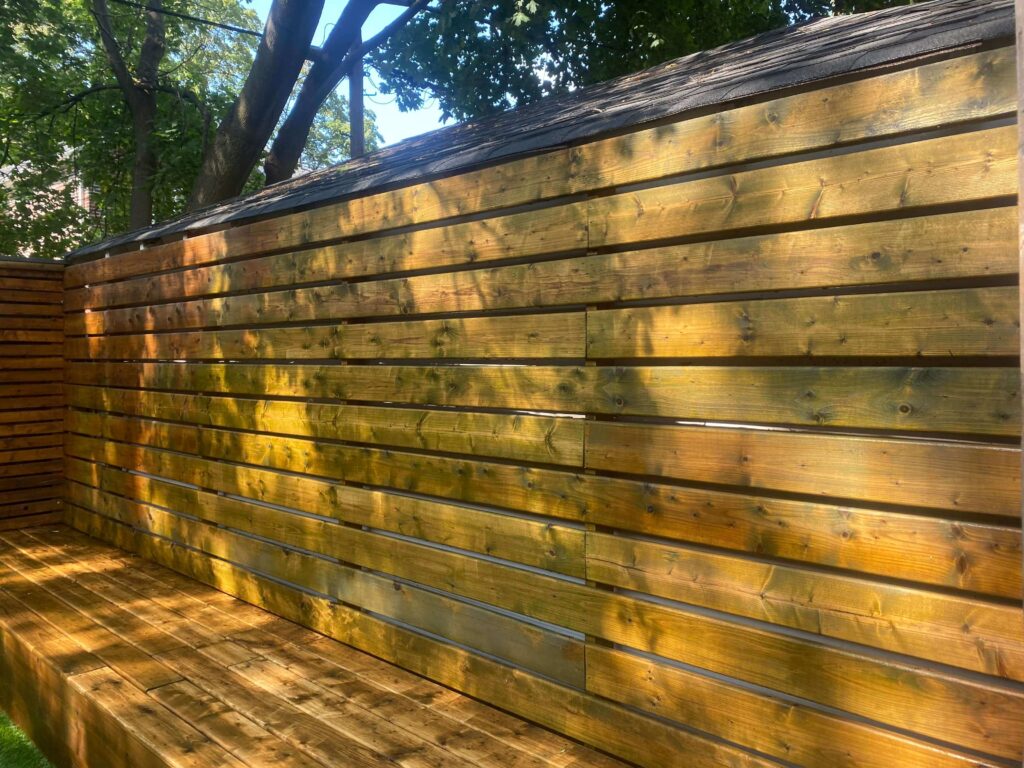 HR Property Maintenance (HRPM) technician power-washing a weathered wooden deck to remove grime and algae.