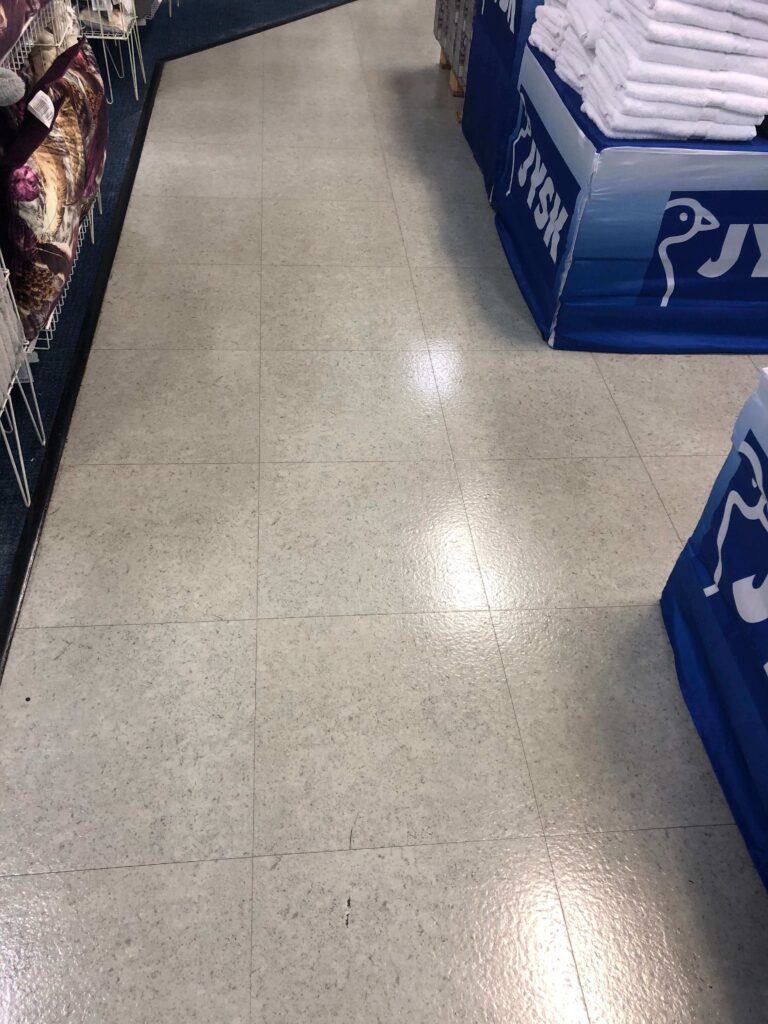 Shiny, freshly waxed vinyl floor reflecting overhead lights after HRPM treatment.