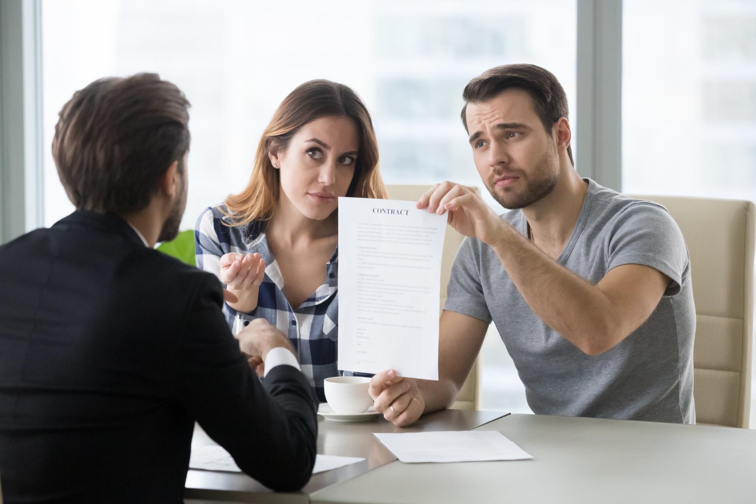 Couple reviewing a contract and discussing terms with a consultant during a meeting.