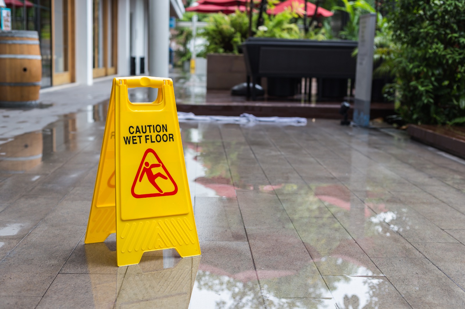 Caution wet floor sign placed on a wet walkway, warning of slip-and-fall hazard