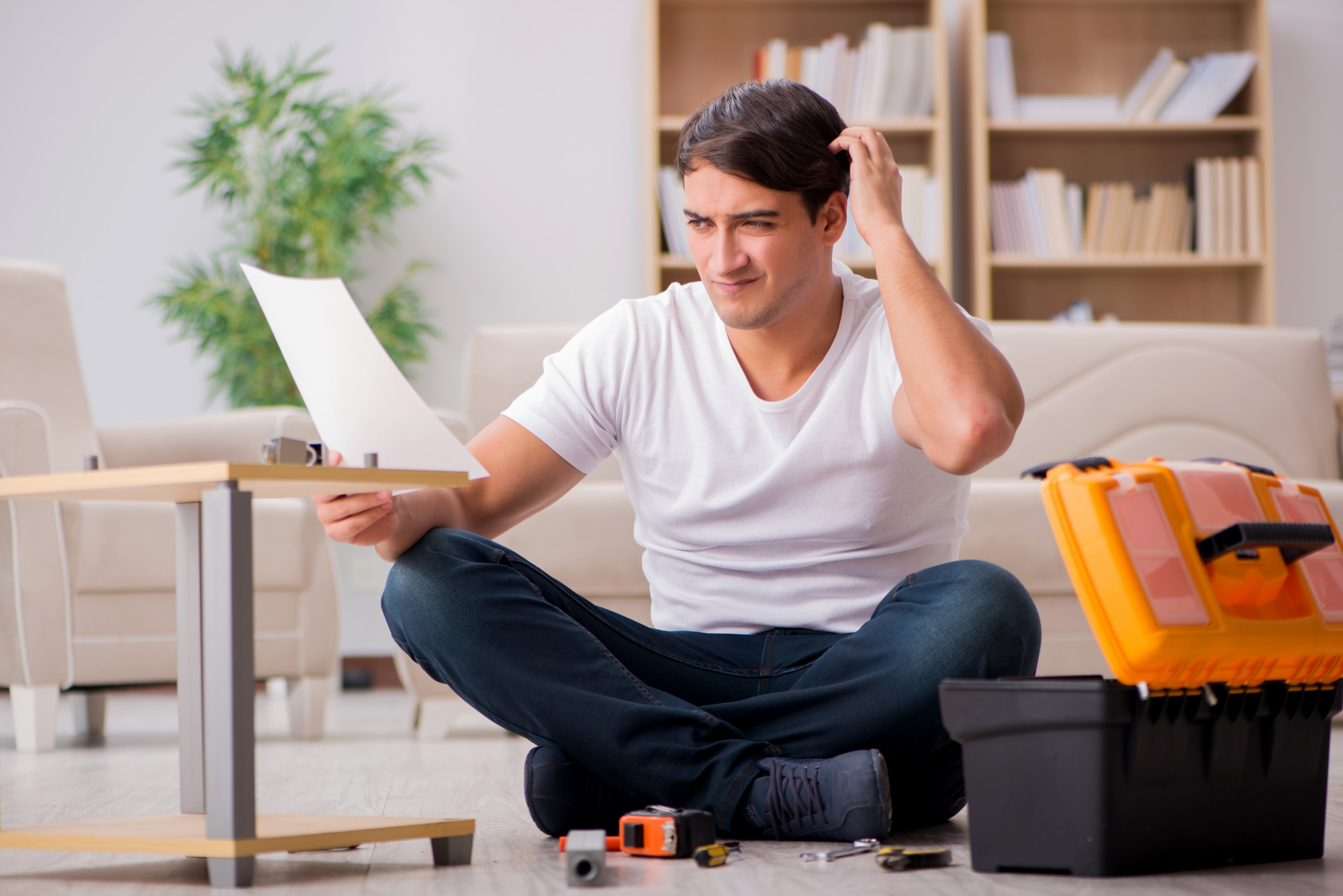 Homeowner reviewing a maintenance document while sitting with tools and a toolbox indoors