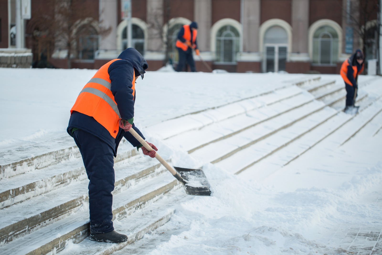 Professional snow removal crew clearing snow from outdoor steps during winter.