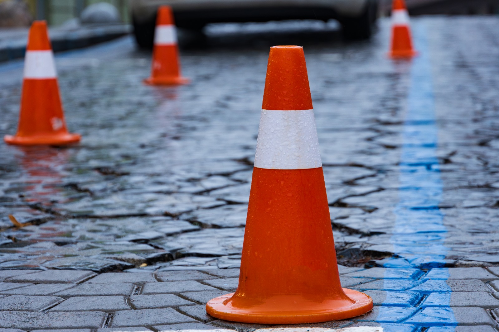 Orange safety cones placed on a wet, slippery walkway to warn pedestrians of fall risk.